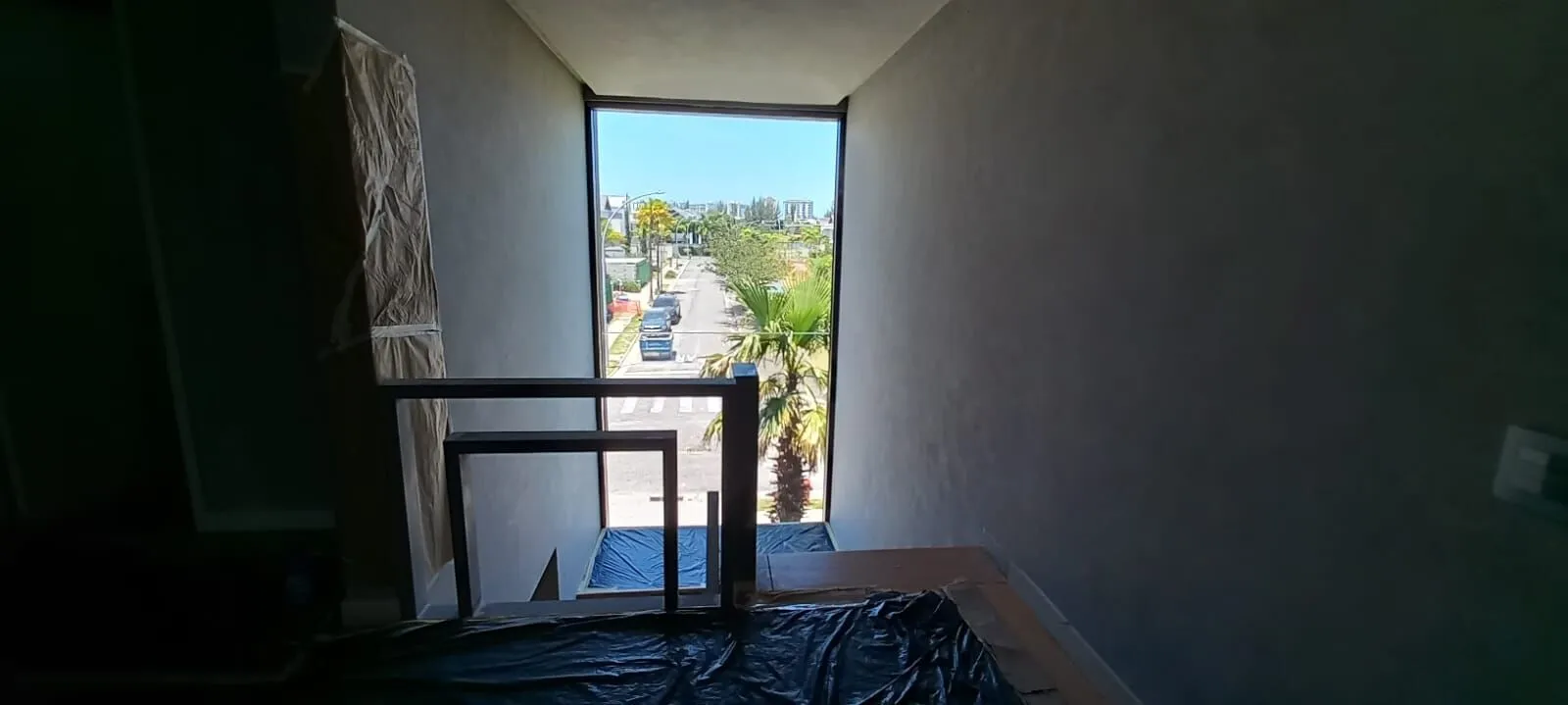 Escada com pé-direito duplo e janelão panorâmico com vista para o condomínio Alphaville Barra da Tijuca