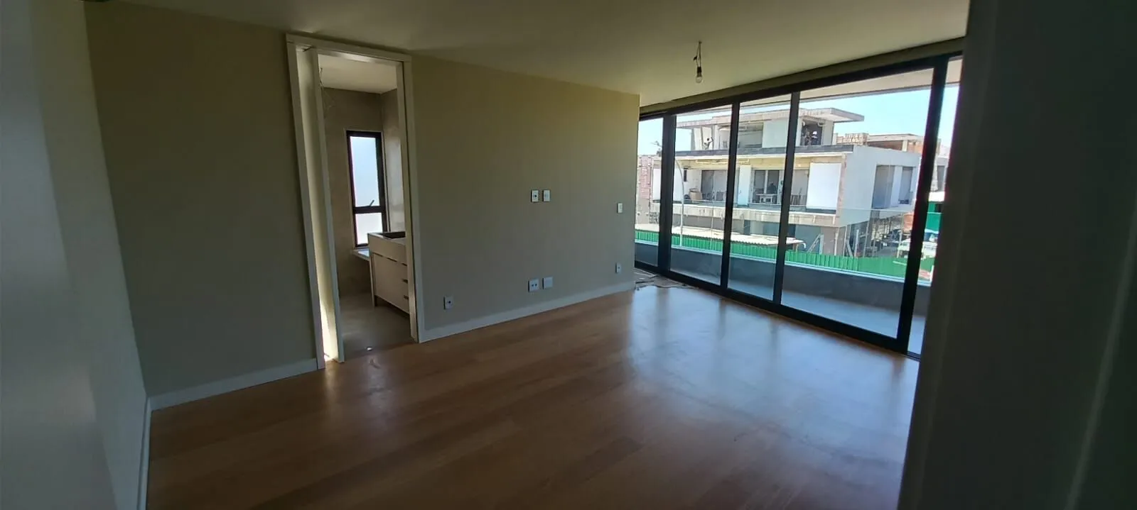 Suíte com piso em madeira nobre, closet e varanda com vista na Mansão 1200m² Alphaville Barra da Tijuca