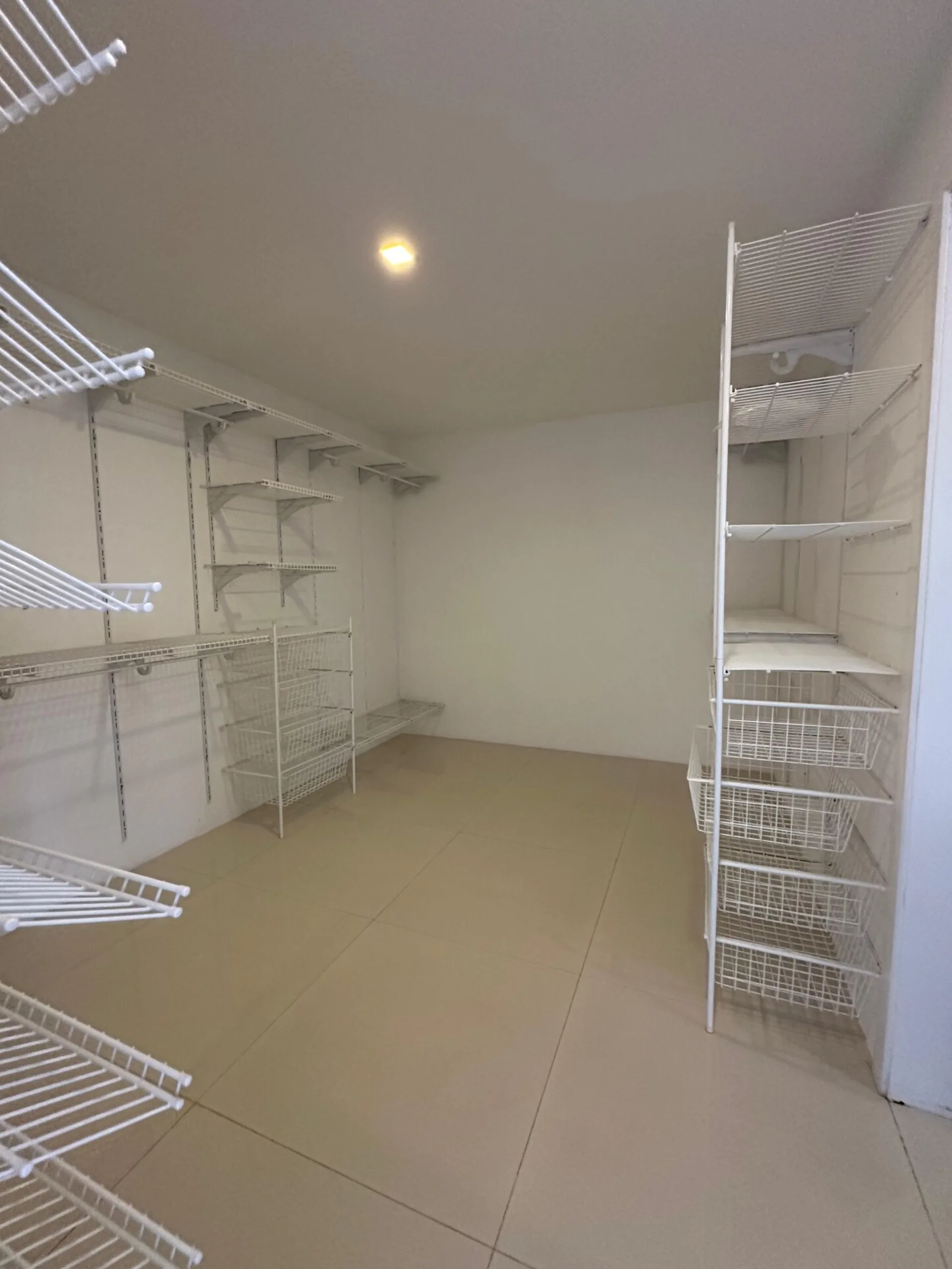 Closet amplo da suíte master com prateleiras e cestos aramados na casa duplex Alphaville 500m²