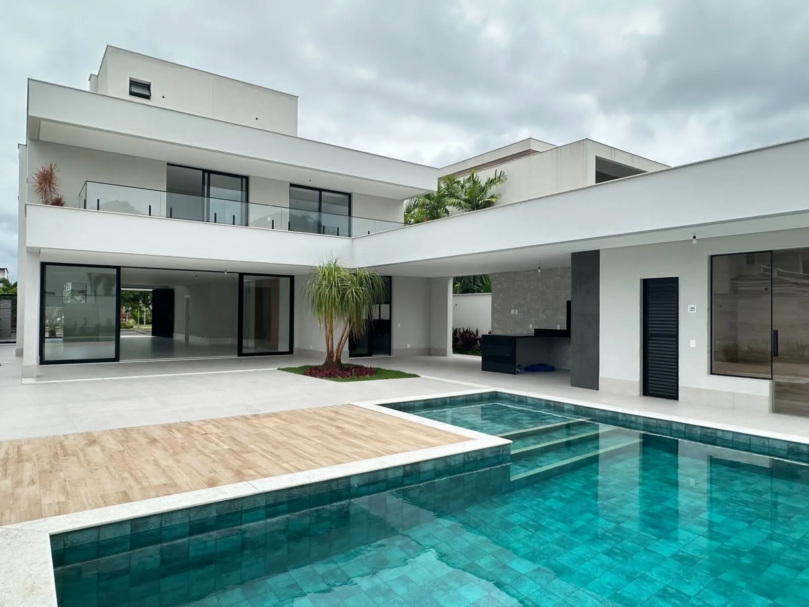 Vista da fachada e piscina com deck de madeira da casa no Alphaville Barra da Tijuca