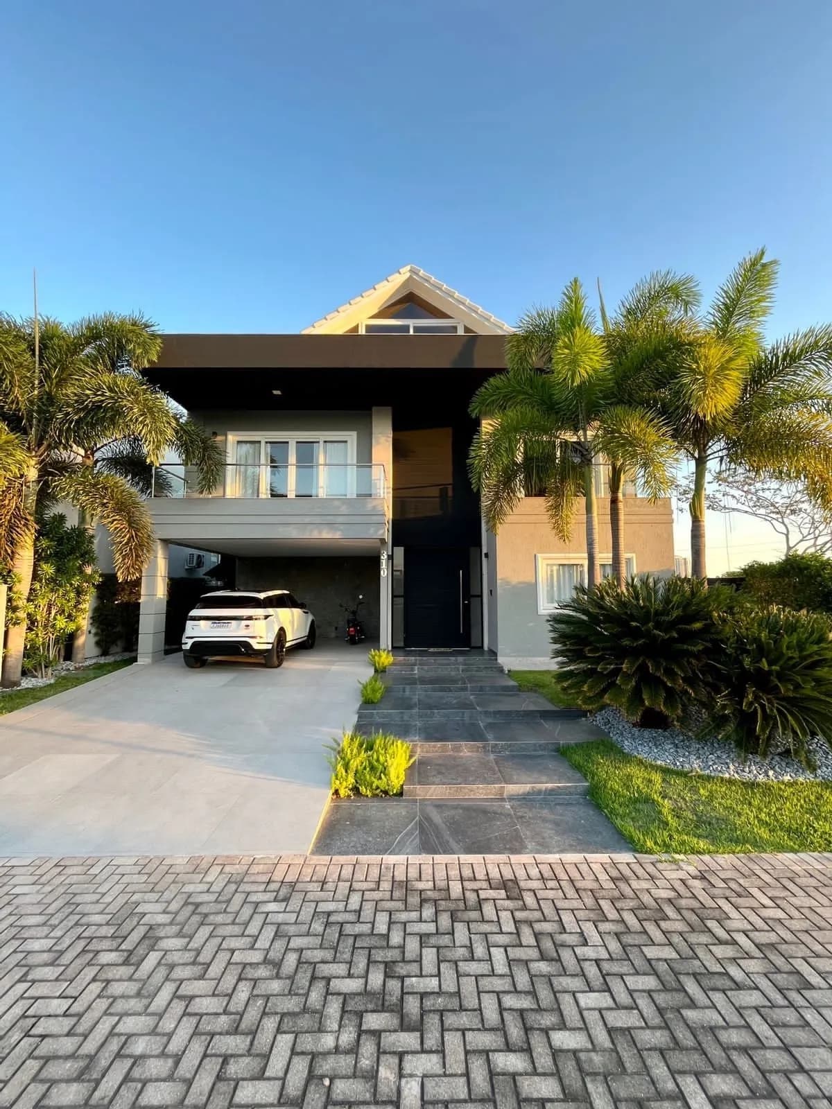Fachada frontal da casa duplex no Alphaville com arquitetura contemporânea e varanda em vidro
