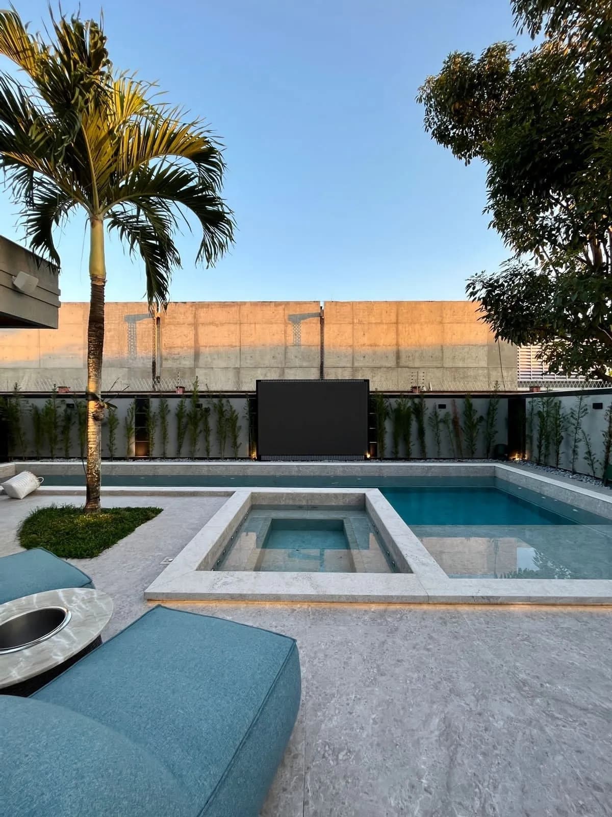 Vista da piscina com área gourmet ao fundo e paisagismo tropical