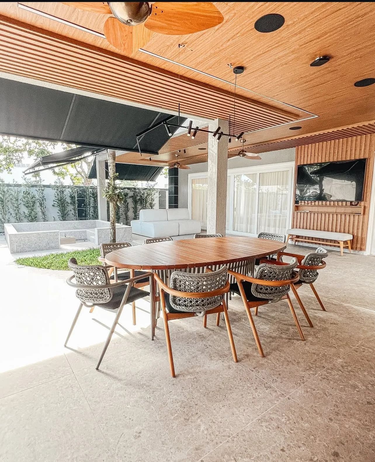 Espaço gourmet externo com teto em madeira ripada e mesa de jantar da Casa Triplex Alphaville 780m²