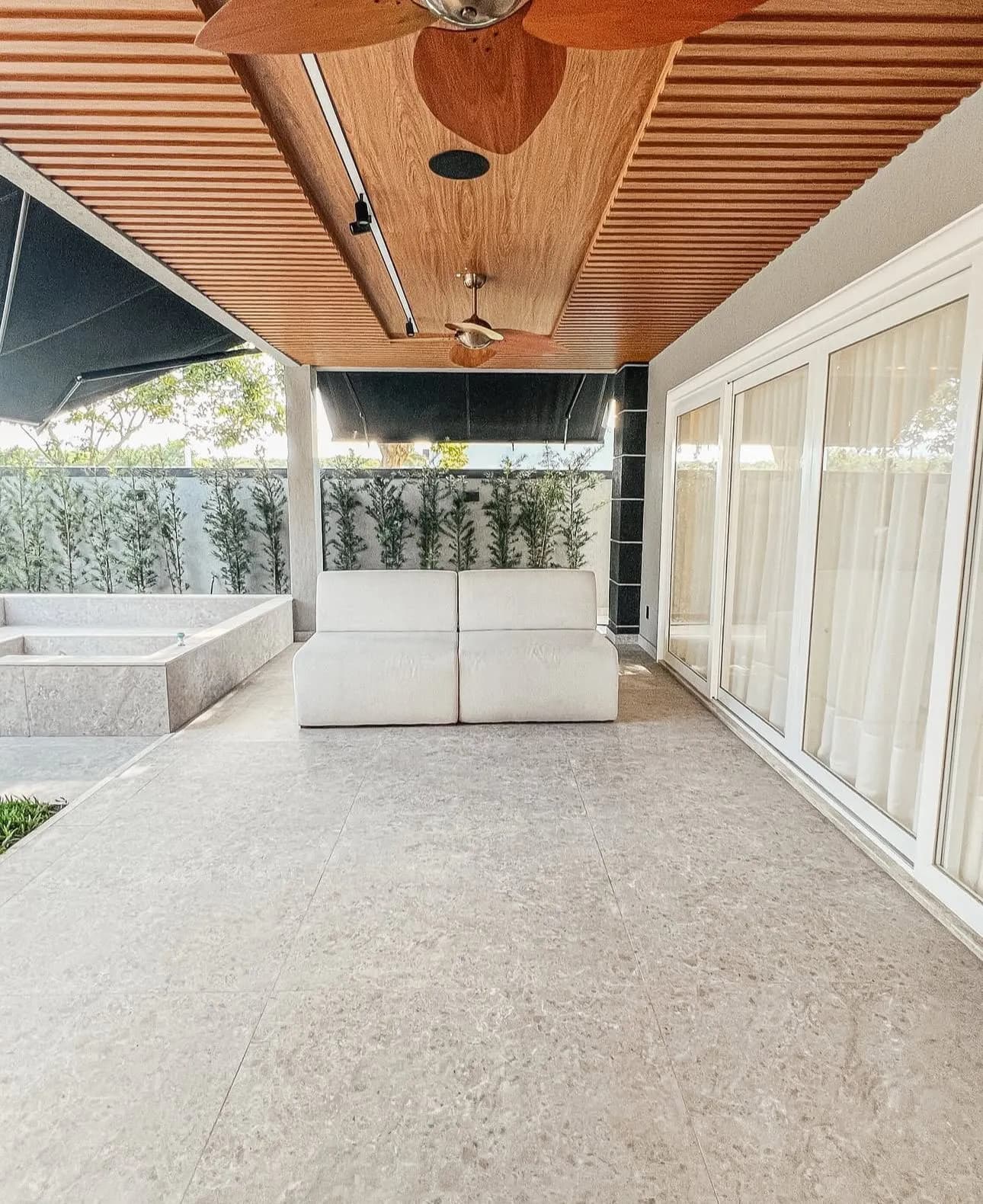 Lounge externo coberto com sofá e vista para piscina da Casa Triplex Alphaville 780m² Barra da Tijuca