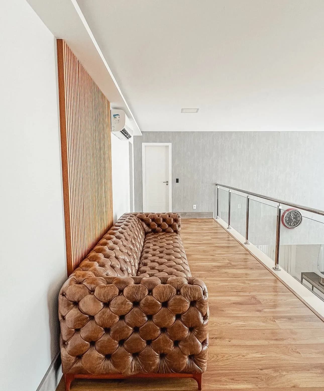 Mezanino com sofá Chesterfield e piso de madeira da Casa Triplex Alphaville 780m²