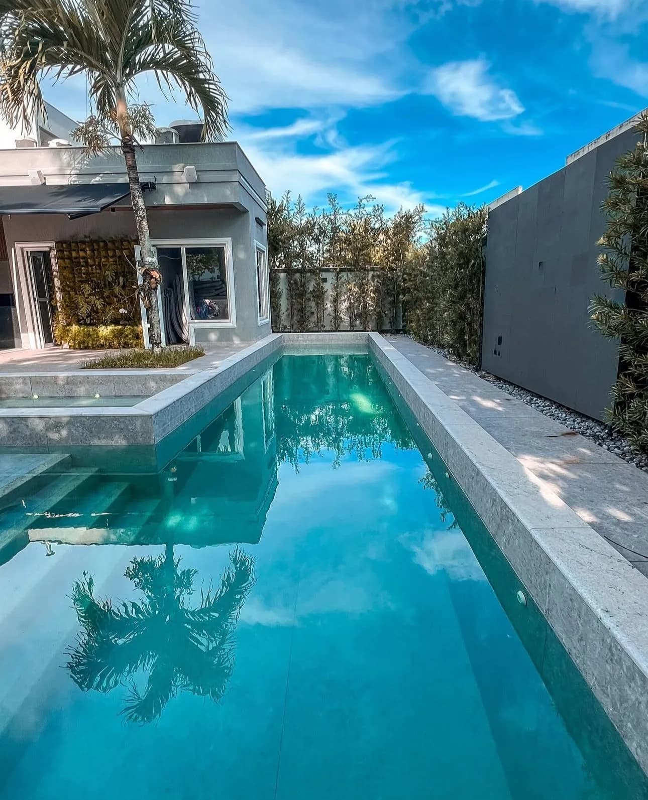 Área da piscina com palmeiras e vista da fachada triplex Alphaville 780m² Barra da Tijuca