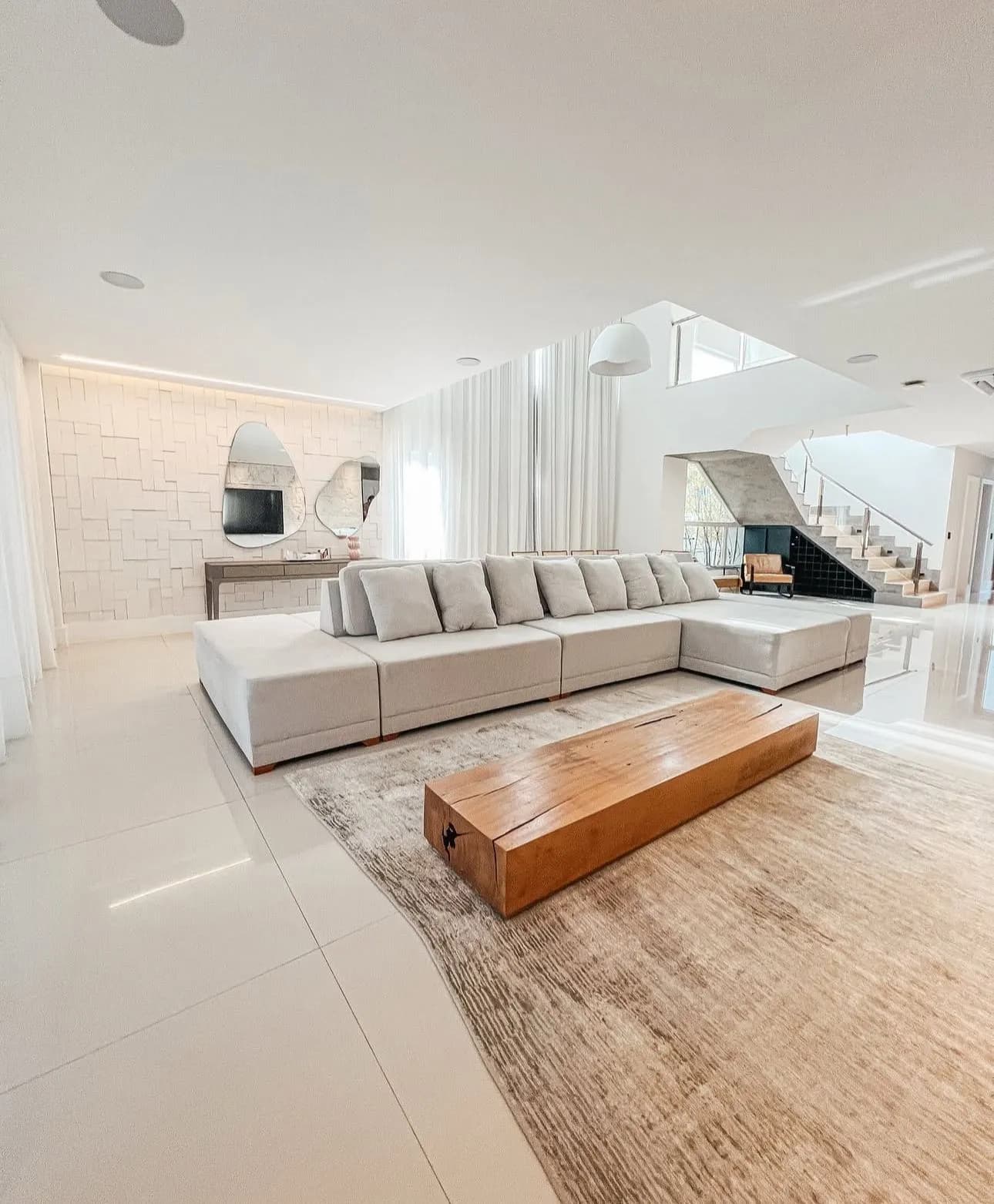 Sala de estar com sofá em L e escada para mezanino da Casa Triplex 780m² Alphaville