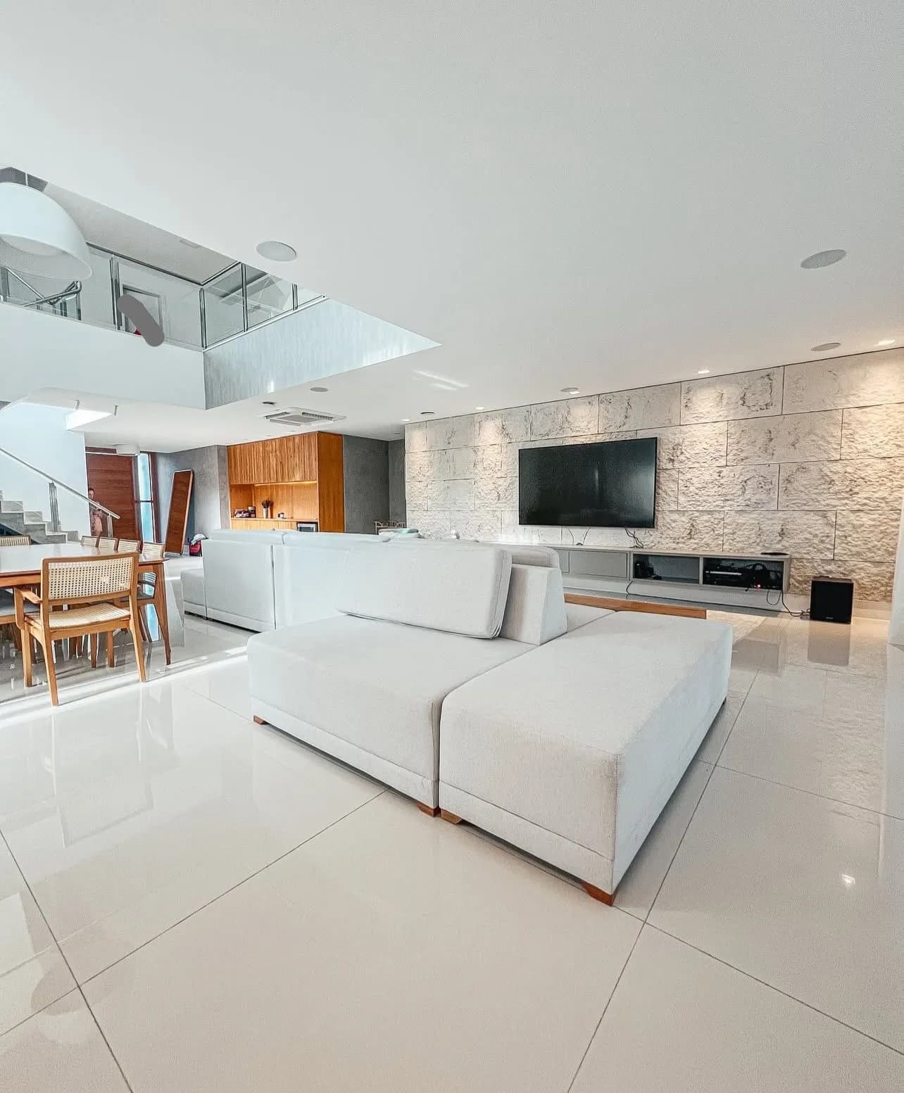 Sala de TV com parede de pedra natural e pé-direito duplo da Casa Triplex Alphaville 780m²