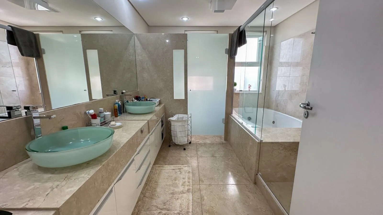 Banheiro da suíte master com banheira de hidromassagem e bancada em mármore na Casa Alphaville 800m²