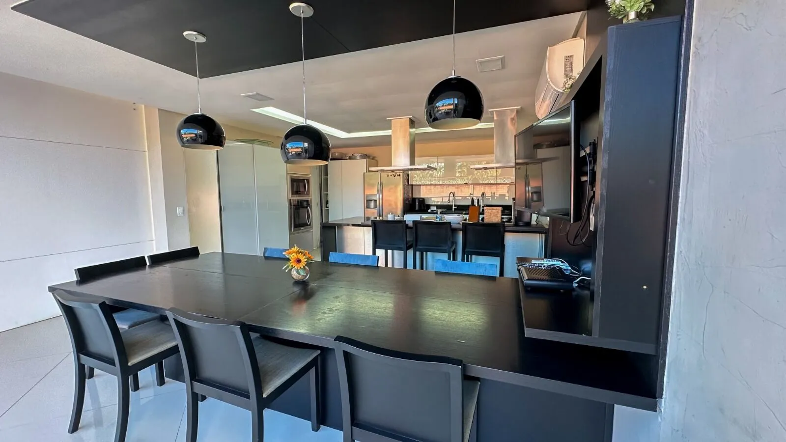 Espaço gourmet integrado com pendentes design, mesa para 8 e cozinha profissional na Casa Alphaville 800m²