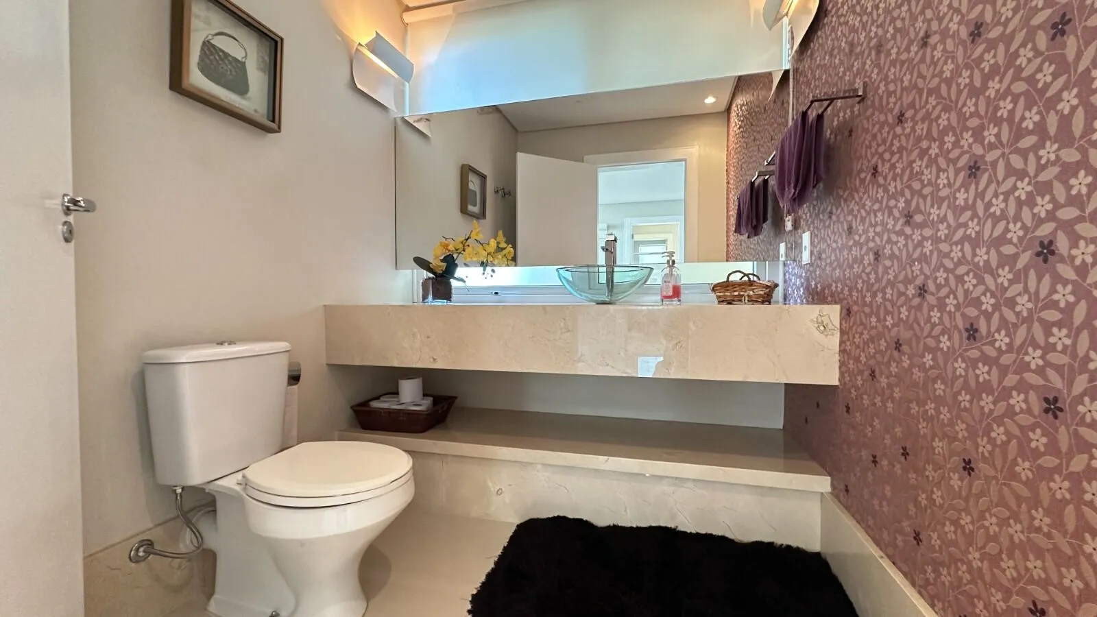 Lavabo social com cuba de vidro e papel de parede floral na Casa Triplex Alphaville Barra da Tijuca