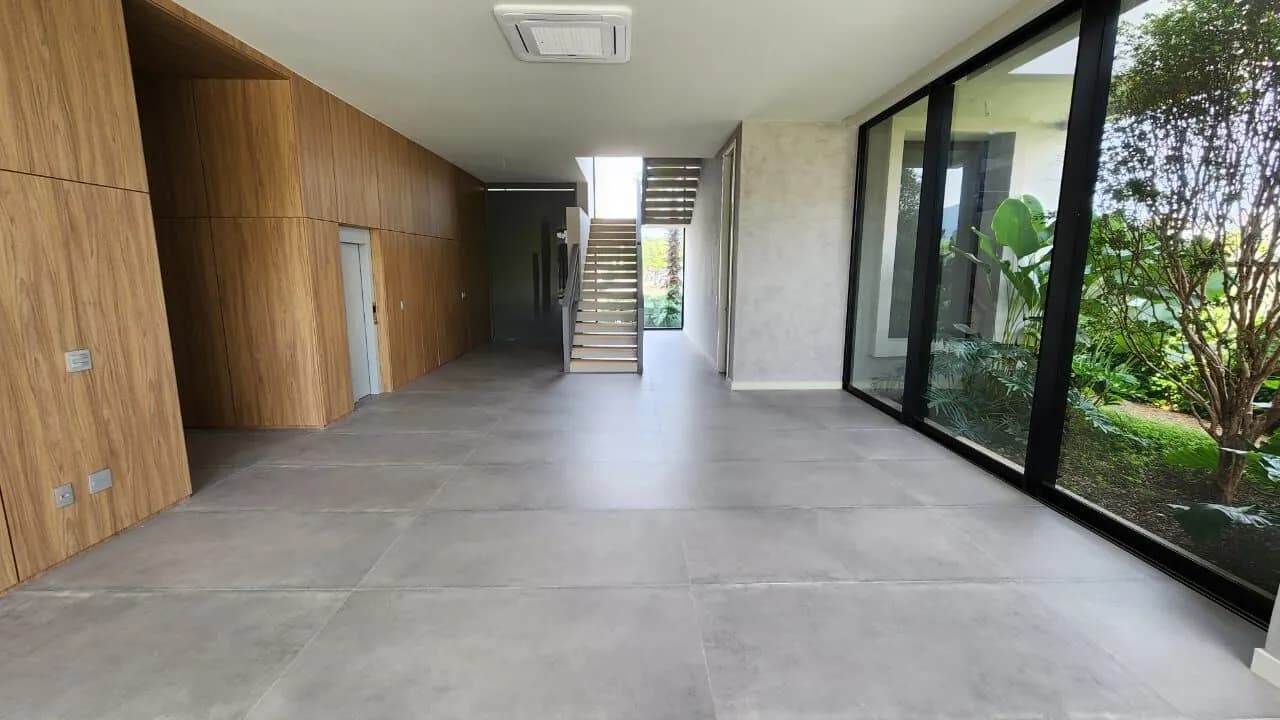 Hall de entrada com painel em madeira, escada escultural e jardim de inverno na Mansão Duplex Alphaville 800m²