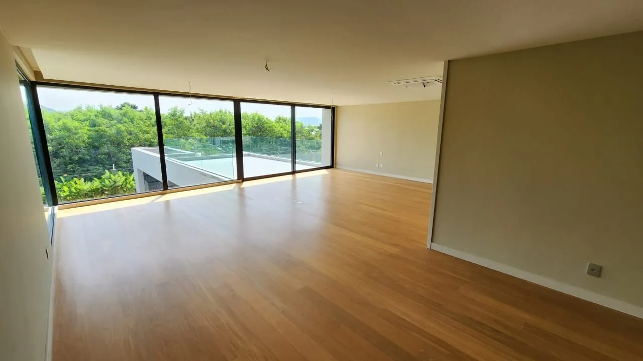 Sala de estar espaçosa com pé-direito duplo e piso porcelanato na Mansão Duplex Alphaville Barra da Tijuca