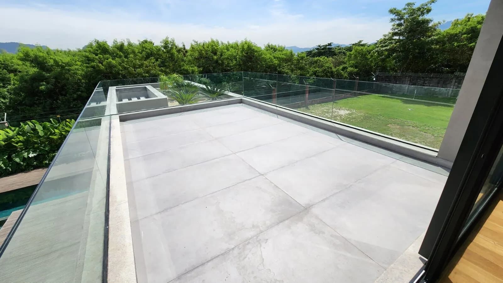 Varanda do pavimento superior com guarda-corpo em vidro e vista para o jardim na Mansão Duplex Alphaville
